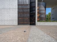 a modern building in the city with black shutters and a door open to an empty courtyard with trees on either side