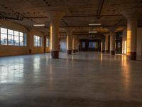 a very large empty space with windows, and a lot of light shining on the floor