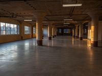 a very large empty space with windows, and a lot of light shining on the floor