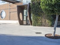 an outdoor area with planters and two small trees, in front of a building