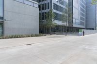 a couple walking through an outside area next to large buildings with plants and trees around