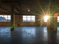 a sun burst in an empty building with no light on it's windows and a large area of concrete