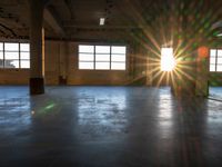 a sun burst in an empty building with no light on it's windows and a large area of concrete