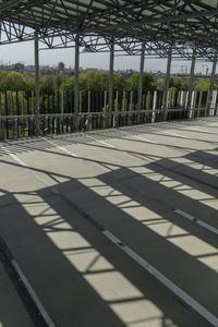 the roof is made from metal bars, and it has shadows on the floor as if of a rail way