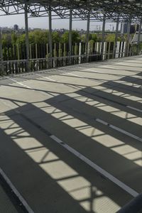 the roof is made from metal bars, and it has shadows on the floor as if of a rail way