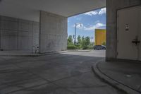 a white door is open in a empty building where there are parking spaces underneath the building