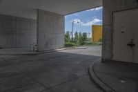 a white door is open in a empty building where there are parking spaces underneath the building