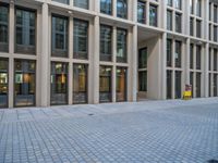 an empty brick courtyard area with two stone columns and two arched windows in the background