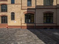 a sidewalk with chairs next to the brick building on the side, some have stairs and some buildings in the background