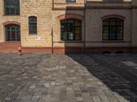 a sidewalk with chairs next to the brick building on the side, some have stairs and some buildings in the background