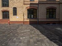 a sidewalk with chairs next to the brick building on the side, some have stairs and some buildings in the background