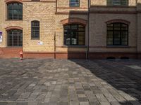 a sidewalk with chairs next to the brick building on the side, some have stairs and some buildings in the background