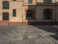 a sidewalk with chairs next to the brick building on the side, some have stairs and some buildings in the background