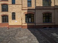 a sidewalk with chairs next to the brick building on the side, some have stairs and some buildings in the background