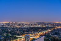 a view of an intersection at night from a hilltop overlooking the city skyline in hollywood