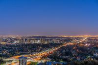 a view of an intersection at night from a hilltop overlooking the city skyline in hollywood