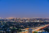 a view of an intersection at night from a hilltop overlooking the city skyline in hollywood