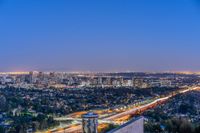 a view of an intersection at night from a hilltop overlooking the city skyline in hollywood