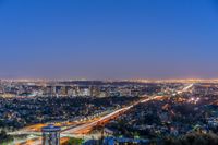 a view of an intersection at night from a hilltop overlooking the city skyline in hollywood