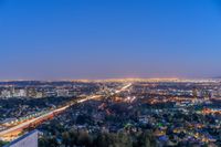 a view of an intersection at night from a hilltop overlooking the city skyline in hollywood