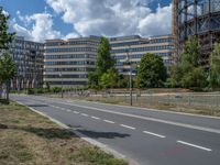 there is an empty street in front of a huge building under construction with trees around