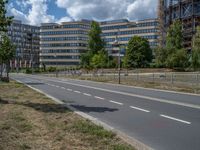 there is an empty street in front of a huge building under construction with trees around