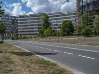 there is an empty street in front of a huge building under construction with trees around