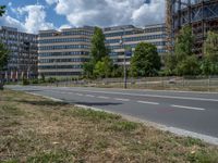 there is an empty street in front of a huge building under construction with trees around