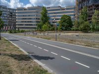 there is an empty street in front of a huge building under construction with trees around