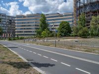 there is an empty street in front of a huge building under construction with trees around