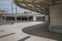 an empty public park with benches and people riding skateboards on the boardwalk at the train station