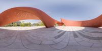 two large orange sculptures sitting next to each other in a park setting with the sky and blue sky as backdrop