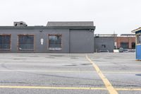 the empty parking lot has only snow on the ground in front of an old brick factory