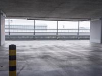 an empty parking garage with big window and traffic signs on the walls, overlooking the street below