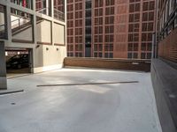 a parking garage in between two brick buildings, with a few pieces of wood stuck out of the floor