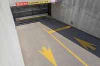 the floor of a parking garage with arrow painted in yellow and grey tones with stairs up to them