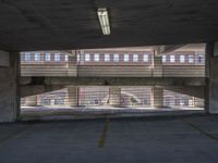 an empty parking garage with multiple windows to the inside of it, overlooking a street