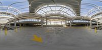 a skateboarder is skating in a building with metal supports on its ceiling and yellow arrows pointing up