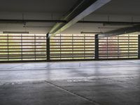 a view from the back of an underground parking garage with concrete floors and striped windows