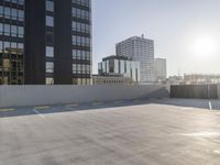 empty parking lot with city view outside of buildings, in front of a wall and sun shining