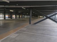 the empty parking garage is very big and shiny in the sunlight with no roof and metal beams