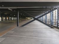 the empty parking garage is very big and shiny in the sunlight with no roof and metal beams