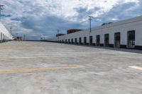 this is an empty industrial building and parking lot under clouds, with no one visible