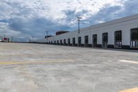 this is an empty industrial building and parking lot under clouds, with no one visible