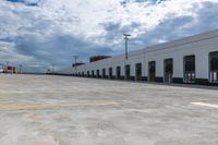 this is an empty industrial building and parking lot under clouds, with no one visible