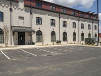 a parking lot next to a large building that has two windows in each of it