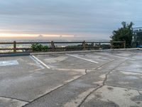 a parking lot with the sun setting in the background, and trees on the other side