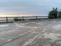 a parking lot with the sun setting in the background, and trees on the other side