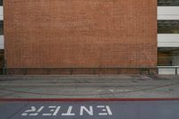 a red brick wall and sidewalk with an exit sign for people to walk around it