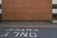 a red brick wall and sidewalk with an exit sign for people to walk around it